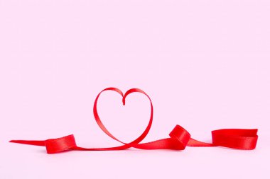 Heart made of red satin ribbon on pink background. Valentine's Day celebration