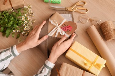 Woman with gift boxes and chamomile flowers for International Women's Day on wooden table, top view