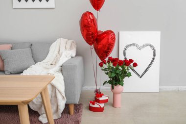 Vase with roses, gifts and balloons for Valentine's Day in interior of living room