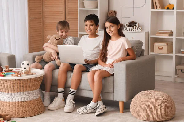 Little friends using laptop on sofa at home