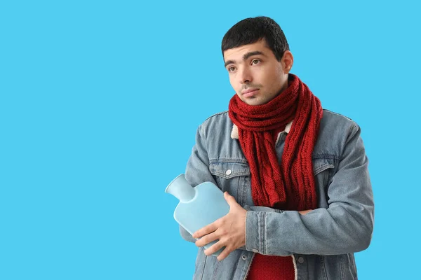 Young Man Warming His Arm Hot Water Bottle Blue Background — Stock Photo, Image