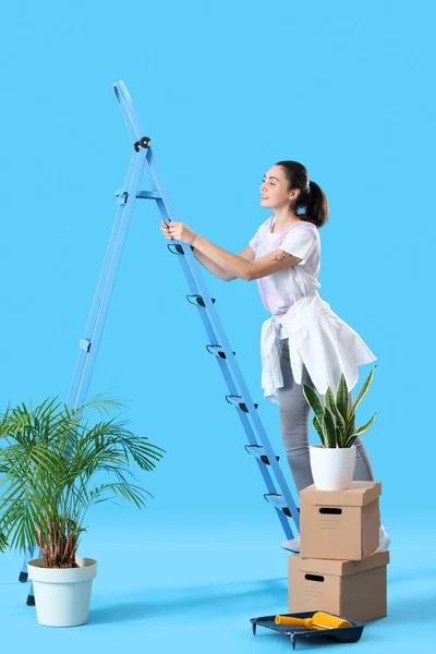 Young Woman Ladder Moving Boxes Blue Background — Stock Photo, Image