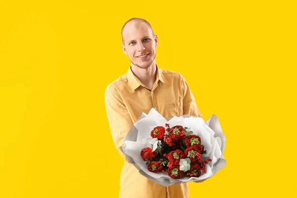 Young man with bouquet of flowers on yellow background. Valentine\'s Day celebration