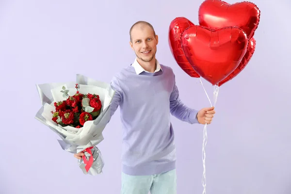 Young man with bouquet of flowers and balloons on lilac background. Valentine\'s Day celebration