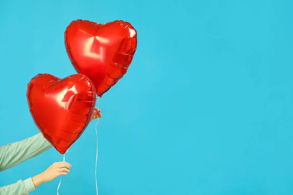 Woman with heart-shaped balloons for Valentine\'s Day on blue background