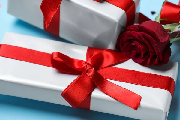 Gift box with beautiful bow and rose flower on blue background. Valentine\'s Day celebration
