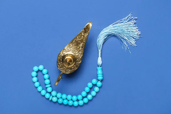 Aladdin lamp of wishes and prayer beads for Ramadan on blue background