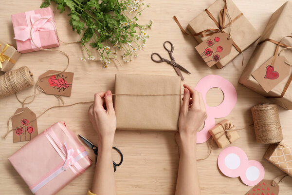 Woman packing presents for International Women's Day celebration on wooden background