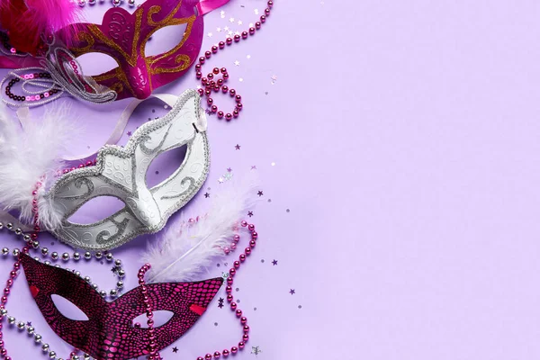 Carnival masks for Mardi Gras celebration with beads and confetti on lilac background
