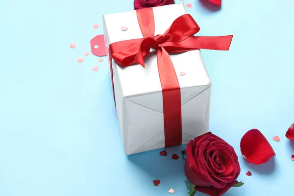 Gift box and rose flower on blue background. Valentine\'s Day celebration