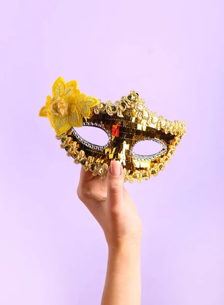 Woman with carnival mask for Purim holiday on lilac background