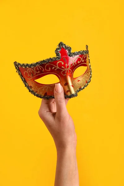 Woman with carnival mask for Purim holiday on orange background