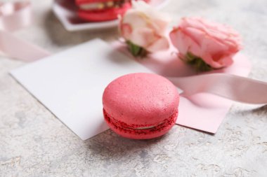 Tasty macaroon, envelopes and rose flowers on grey background. Valentine's Day celebration