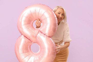 Beautiful mature woman with balloon in shape of figure 8 on lilac background. International Women's Day