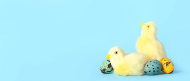 Cute yellow chickens and Easter eggs on light blue background with space for text