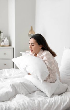Young woman having menstrual cramps in bedroom