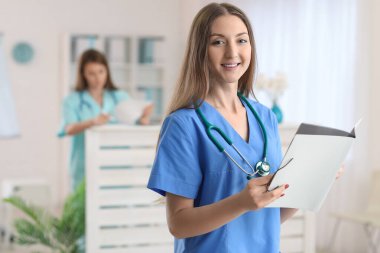 Female medical assistant with folder in clinic