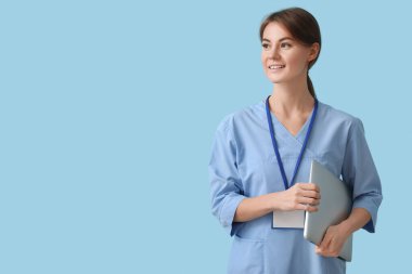 Female medical intern with laptop on blue background