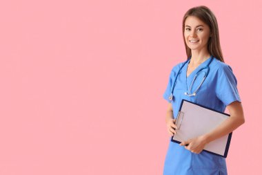 Female medical intern with clipboard on pink background