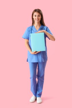 Female medical intern with folder on pink background