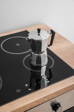 Geyser coffee maker on electric stove in kitchen near grey wall