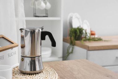 Wicker coaster with geyser coffee maker and cup on kitchen counter