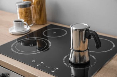 Geyser coffee maker on electric stove in kitchen near grey wall