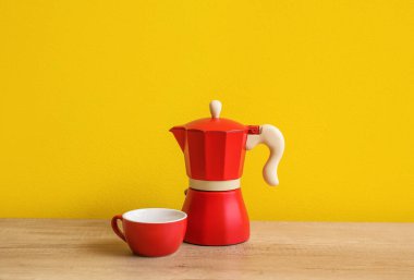 Geyser coffee maker and cup on kitchen counter near yellow wall