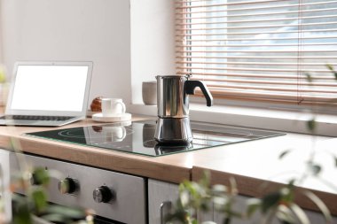 Geyser coffee maker on electric stove in kitchen near window