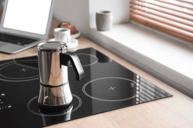 Geyser coffee maker on electric stove in kitchen near window