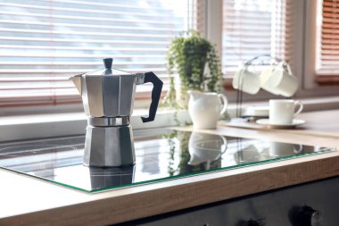 Geyser coffee maker on electric stove in kitchen near window