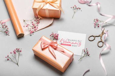 Composition with beautiful gift boxes, packing materials, greeting card and gypsophila flowers on light background. Women's Day celebration