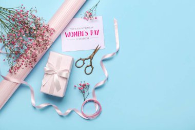Composition with gift box, gypsophila flowers, wrapping paper and greeting card on color background. Women's Day celebration