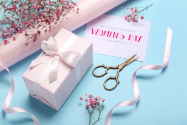 Composition with gift box, gypsophila flowers, wrapping paper and greeting card on color background. Women's Day celebration