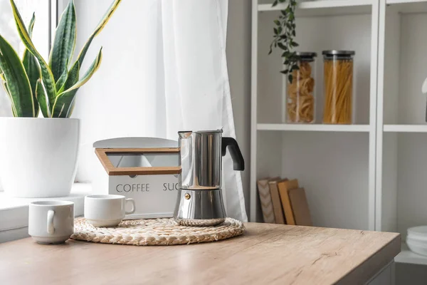 Wicker coaster with geyser coffee maker on kitchen counter near window
