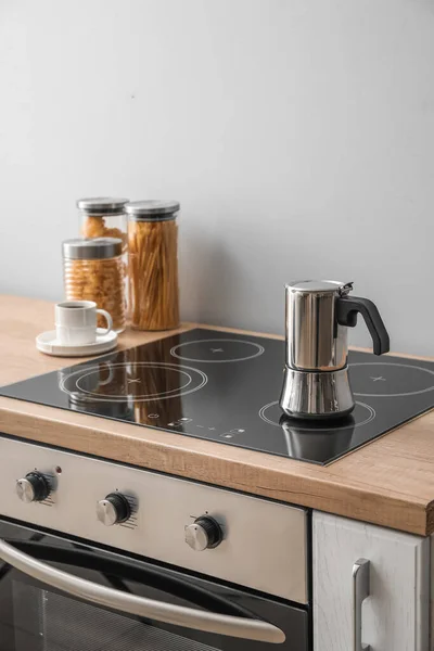 Geyser coffee maker on electric stove in kitchen near grey wall