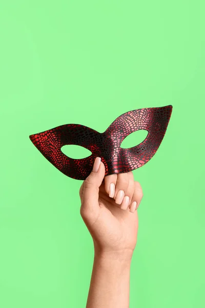 Woman with carnival mask for Purim holiday on green background