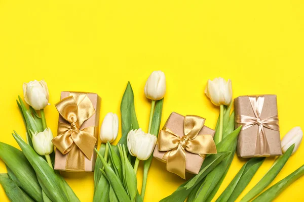 Beautiful tulip flowers and gifts for Women's Day celebration on yellow background