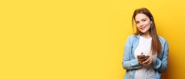 Beautiful young woman with mobile phone listening to music on yellow background with space for text