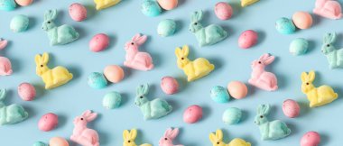 Many Easter bunnies and eggs on light blue background. Pattern for design