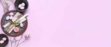 Table setting with Easter eggs and flowers on lilac background with space for text