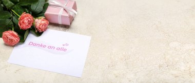 Card with text DANKE AN ALLE, roses and gift on grunge background with space for text