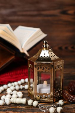Muslim lantern with dates and tasbih for Ramadan on dark wooden table, closeup