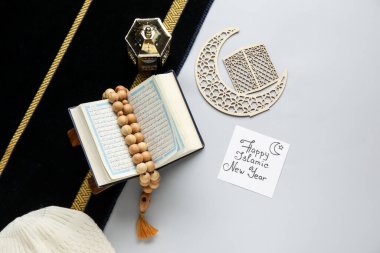 Card with text HAPPY ISLAMIC NEW YEAR, crescent, Koran and prayer beads on light background