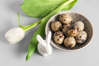 Nest with Easter eggs, bunny and tulip flower on grey background