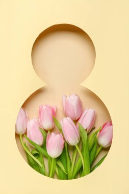 Tulip flowers visible through cut color paper in shape of figure 8. Women's Day celebration