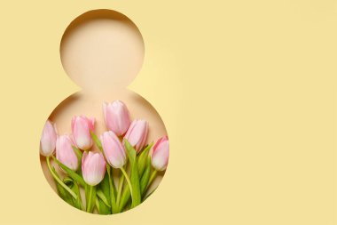 Tulip flowers visible through cut color paper in shape of figure 8. Women's Day celebration