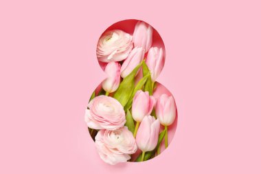 Spring flowers visible through cut pink paper in shape of figure 8. Women's Day celebration