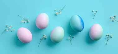 Beautiful Easter eggs and flowers on light blue background
