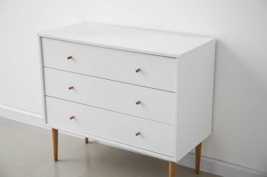 White chest of drawers near light wall